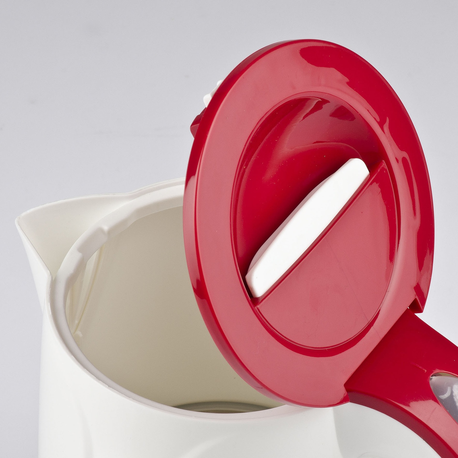 Primo piano di un bollitore elettrico bianco e rosso. Il coperchio rosso è aperto, rivelando l'interno.