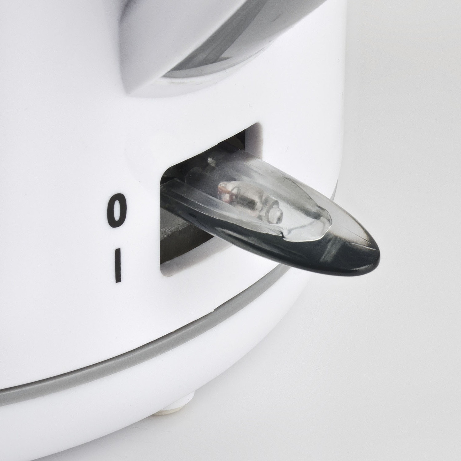 Primo piano di un elettrodomestico bianco con un interruttore trasparente con punta nera. L'interruttore è in posizione 'on'. Segni neri '0' e '-'.