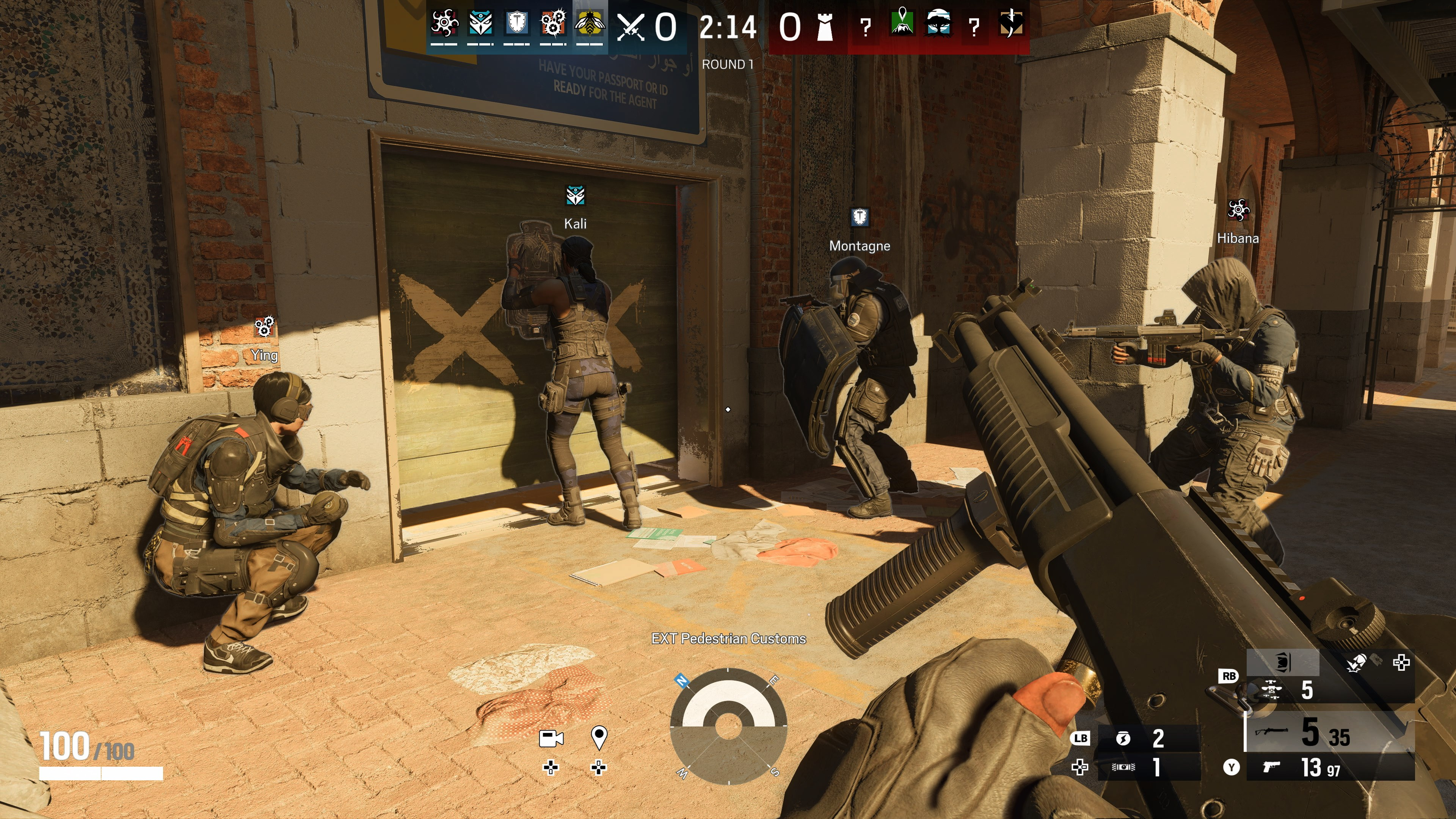 Eine Ego-Shooter-Spielszene mit Charakteren, die Waffen anvisieren. Einer hockt, andere stehen in der Nähe einer Tür, mit einer Waffe im Vordergrund.