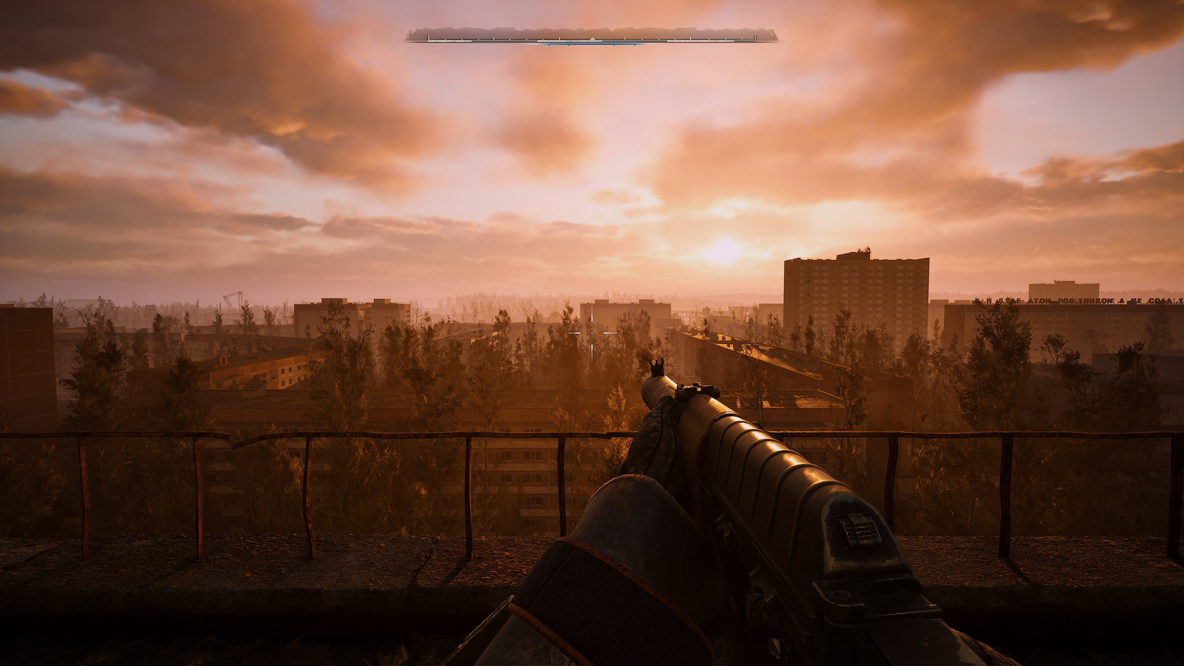 Vue à la première personne d'un paysage urbain au coucher du soleil. Une arme est au premier plan. Des bâtiments, des arbres et des nuages remplissent le ciel orange.