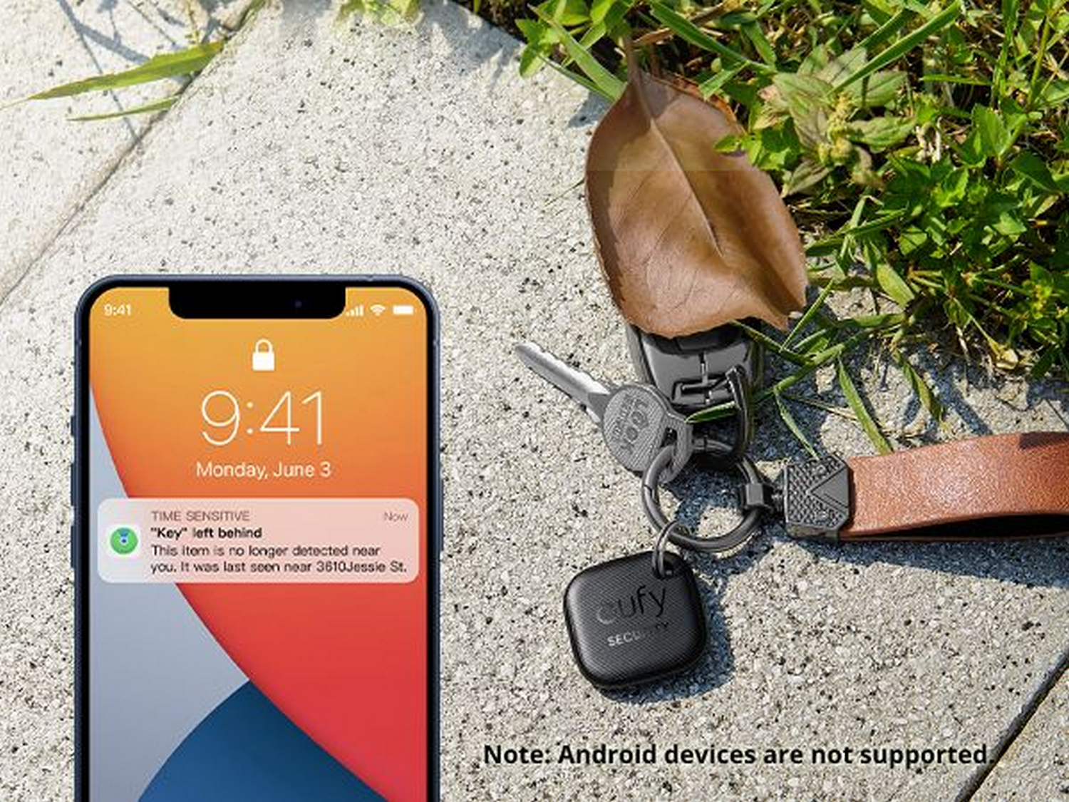 Smartphone con notificación. Llaves, un localizador de llaves y una hoja en el suelo. Se ve hierba y superficie de hormigón.