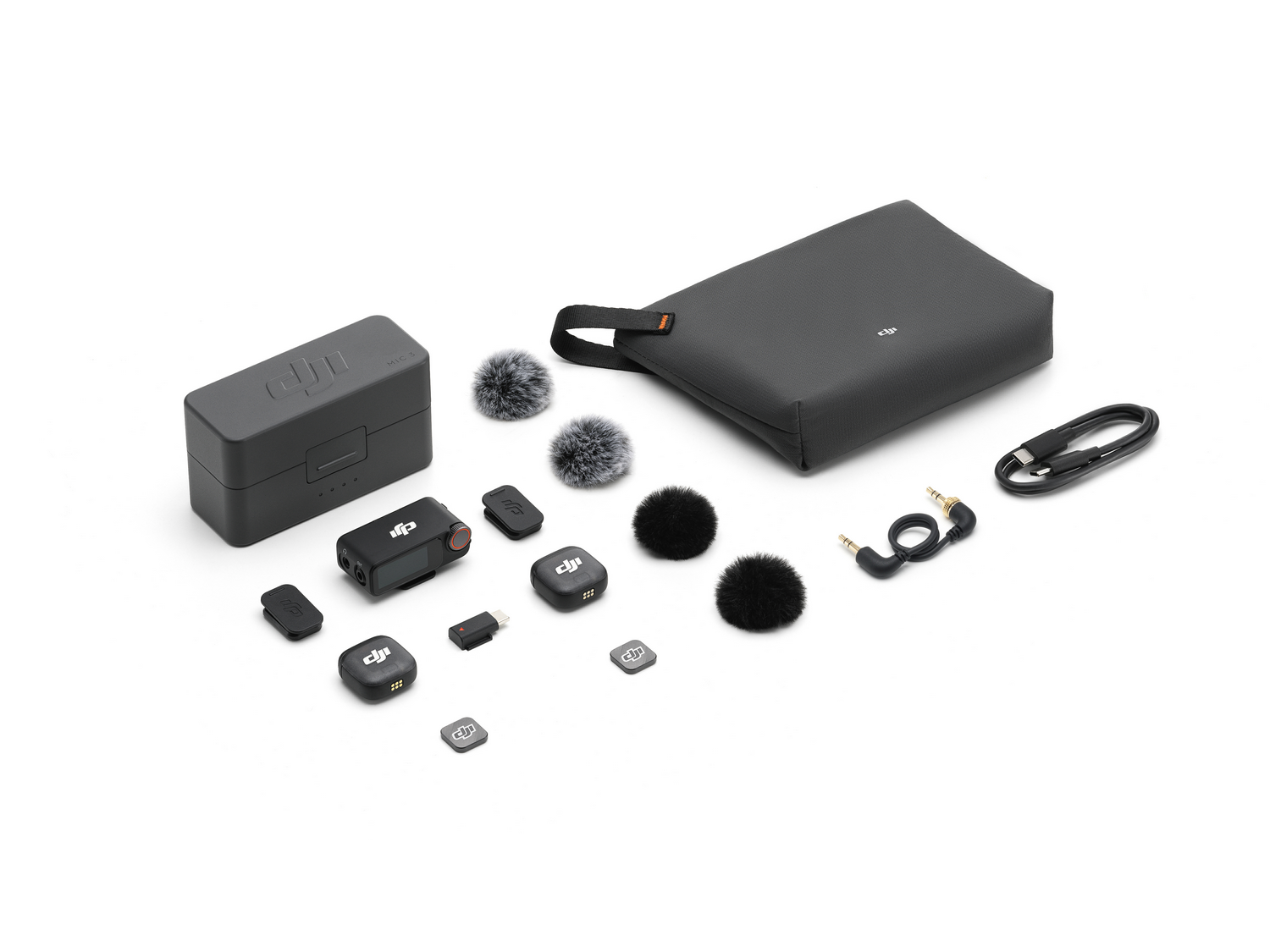 Una colección de equipos de audio negros: micrófonos, un estuche de carga, una bolsa de transporte, cables y adaptadores, colocados sobre una superficie blanca.