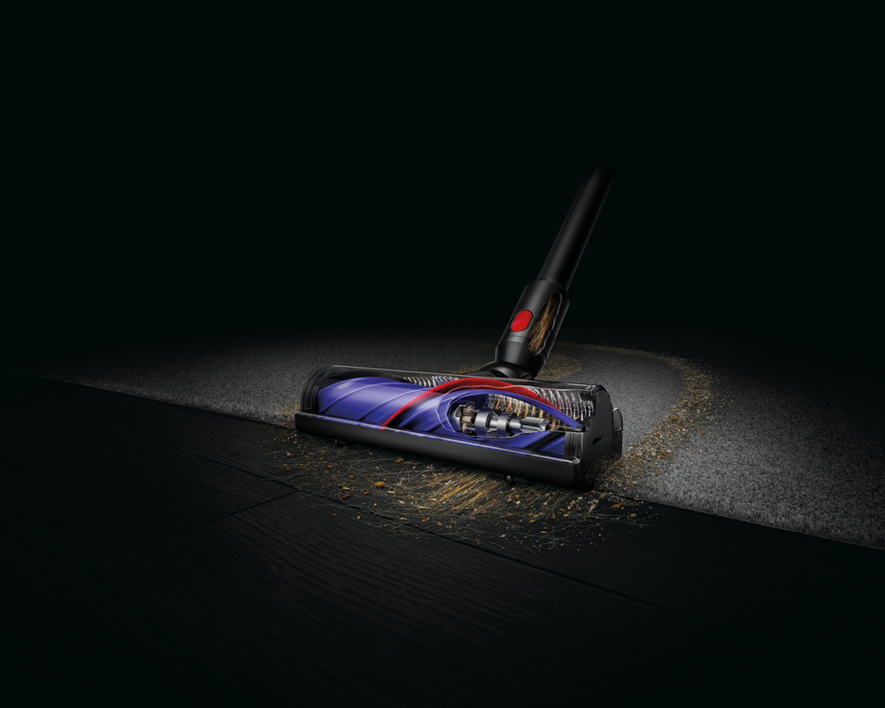 Głowica odkurzacza na dywanie, pokazująca elementy wewnętrzne. Obecny kurz i zanieczyszczenia. Ciemne tło, drewniana podłoga na pierwszym planie.