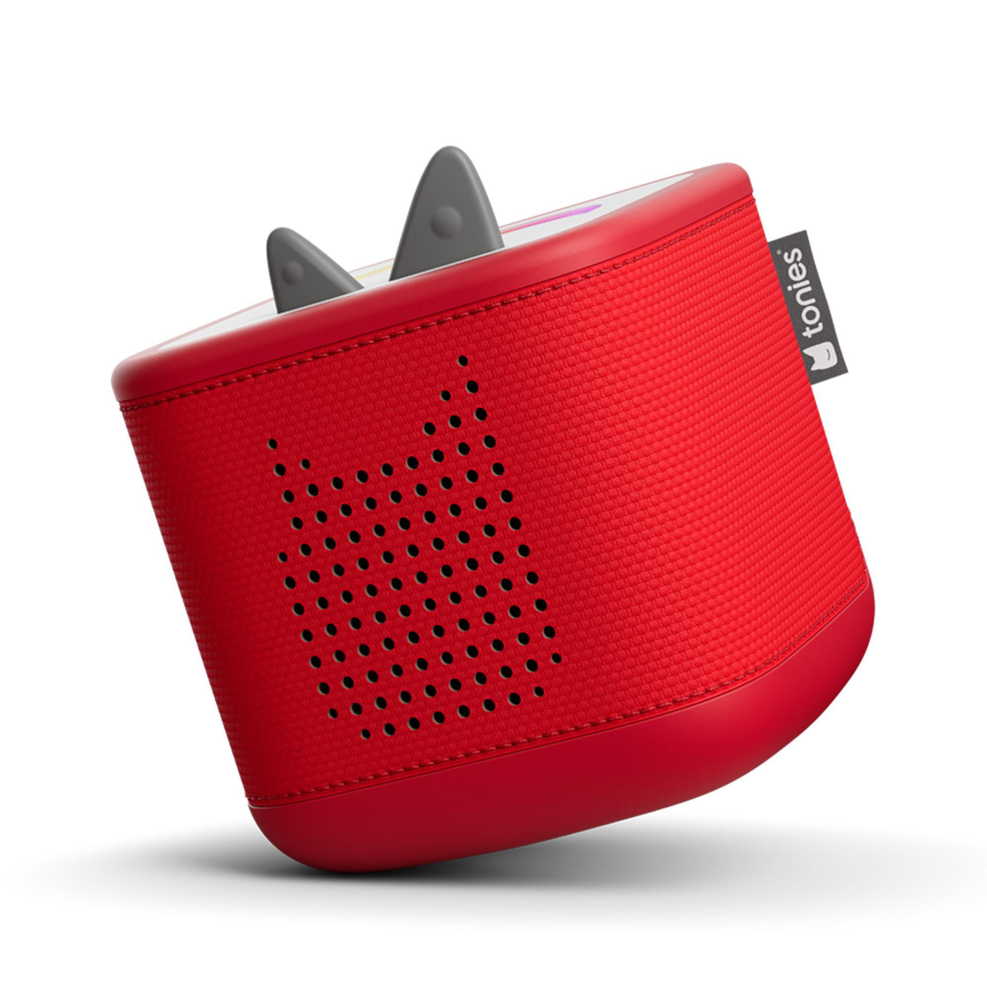 Eine rote Toniebox mit zwei grauen Ohren. Sie ist geneigt und zeigt die Lautsprecherlöcher und das 'tonies'-Logo.