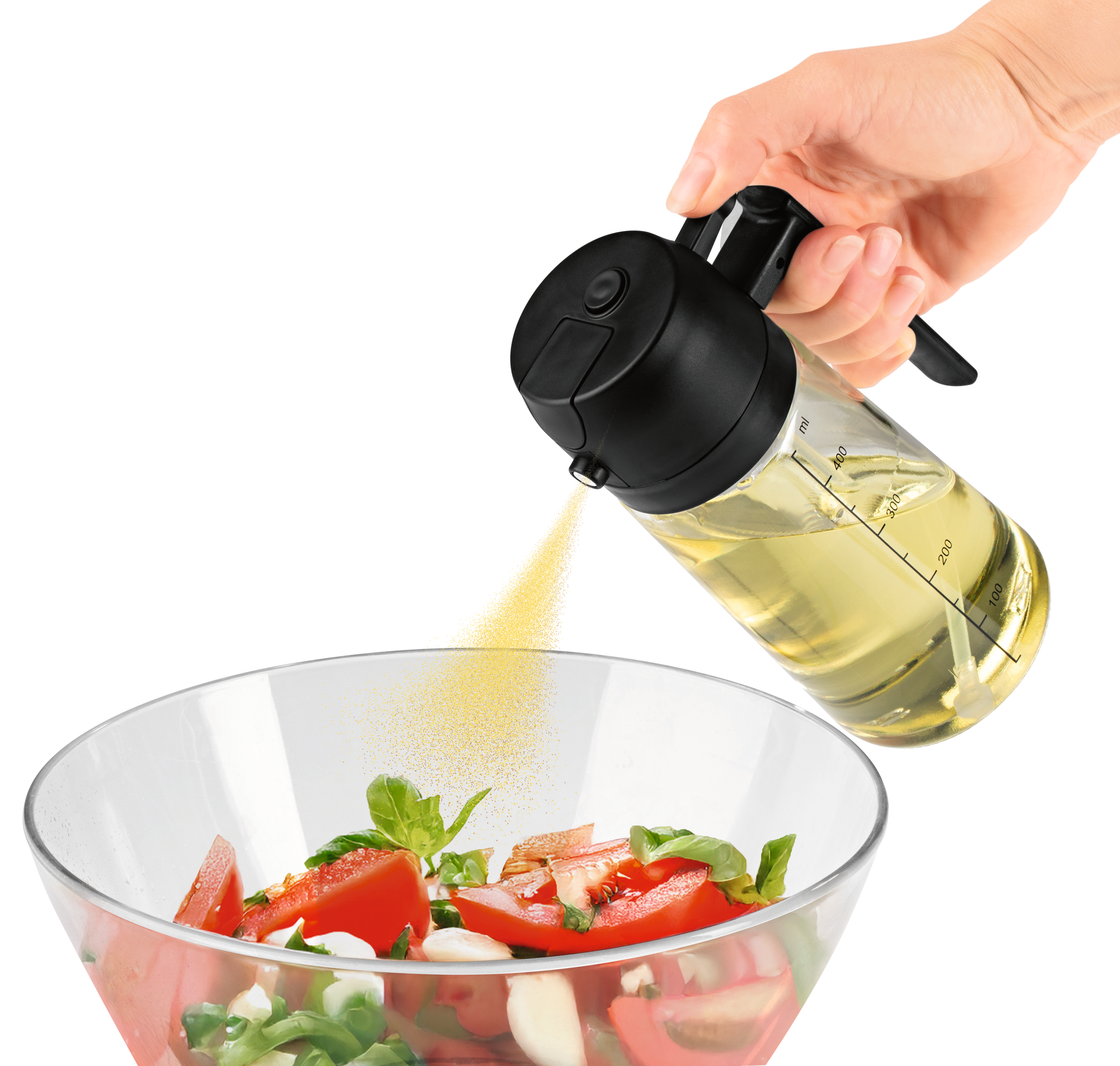 Eine Hand gießt Öl über einen Salat in einer Glasschüssel. Tomaten, Basilikum und Mozzarella sind sichtbar.