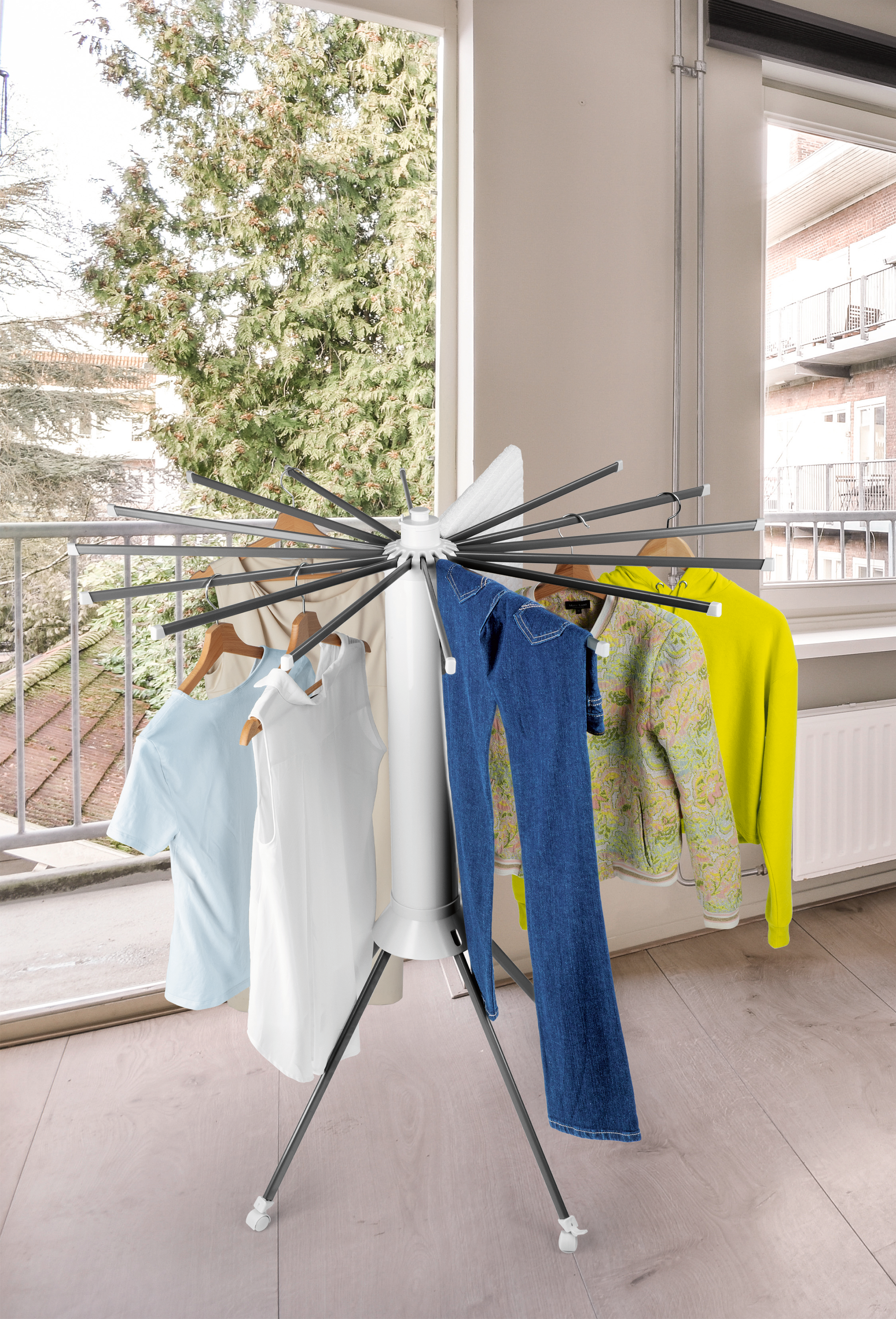 Wäscheständer mit Jeans, Jacken und Hemden. Außenansicht durch Fenster mit Bäumen.
