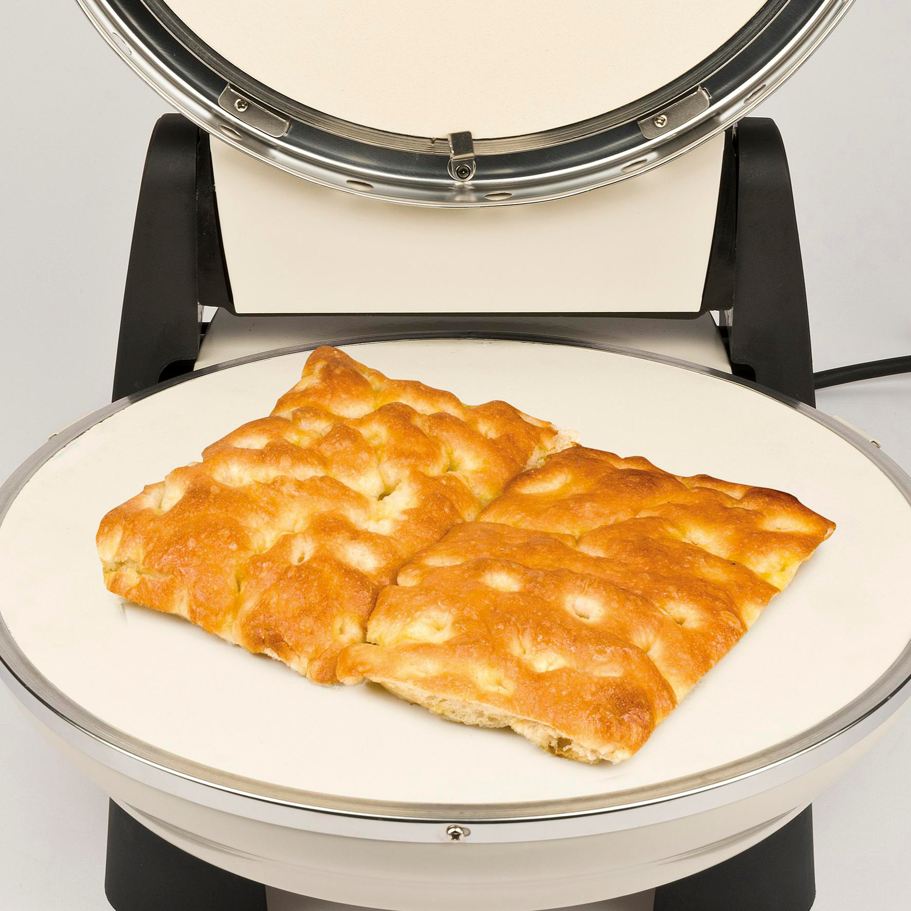 Focaccia-Brot auf einem Pizzaofen. Das Brot ist goldbraun mit Luftblasen. Der Ofen ist silber und schwarz.