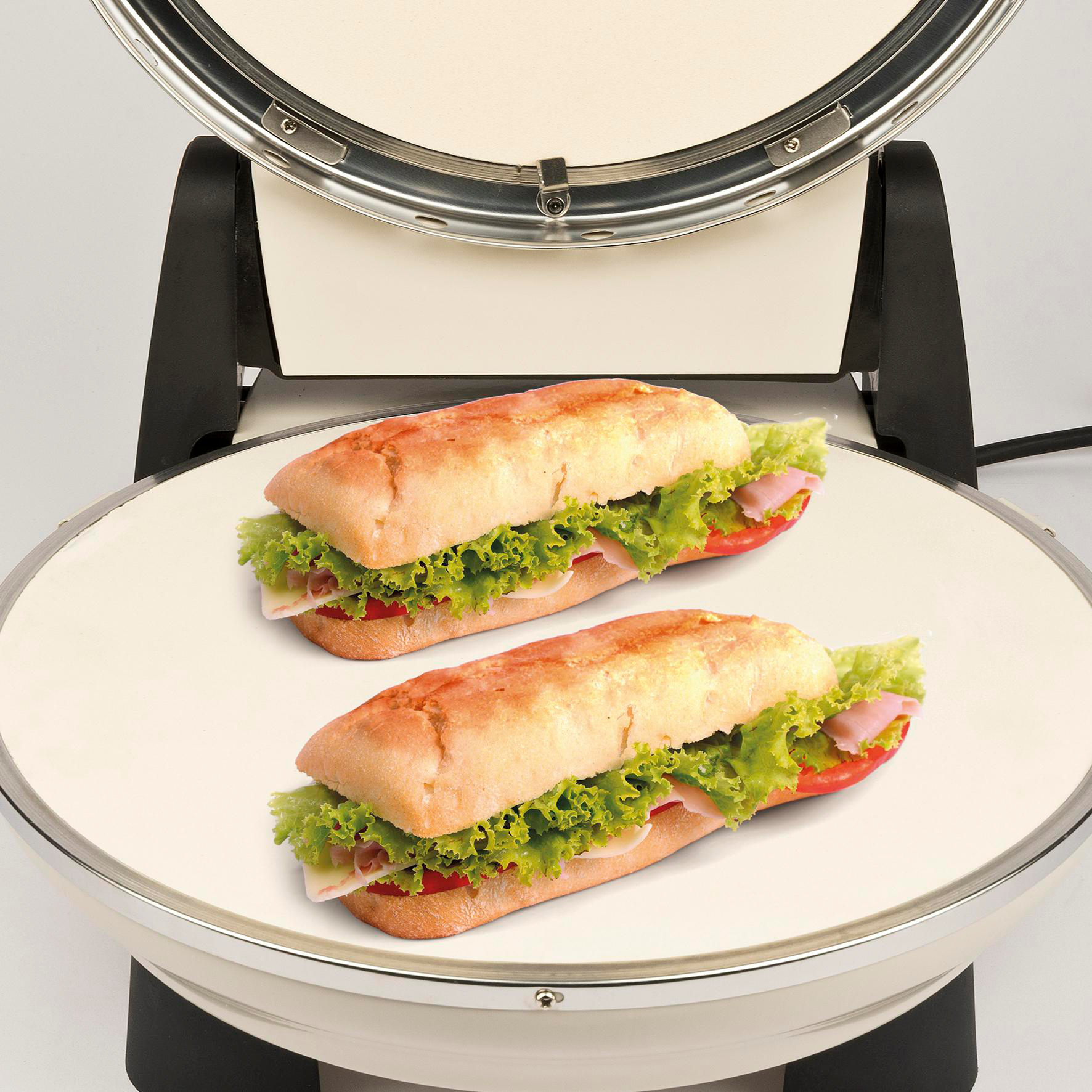 Zwei Sandwiches mit Salat, Tomaten, Schinken und Käse auf einer weißen Oberfläche, in einem Sandwichmaker.