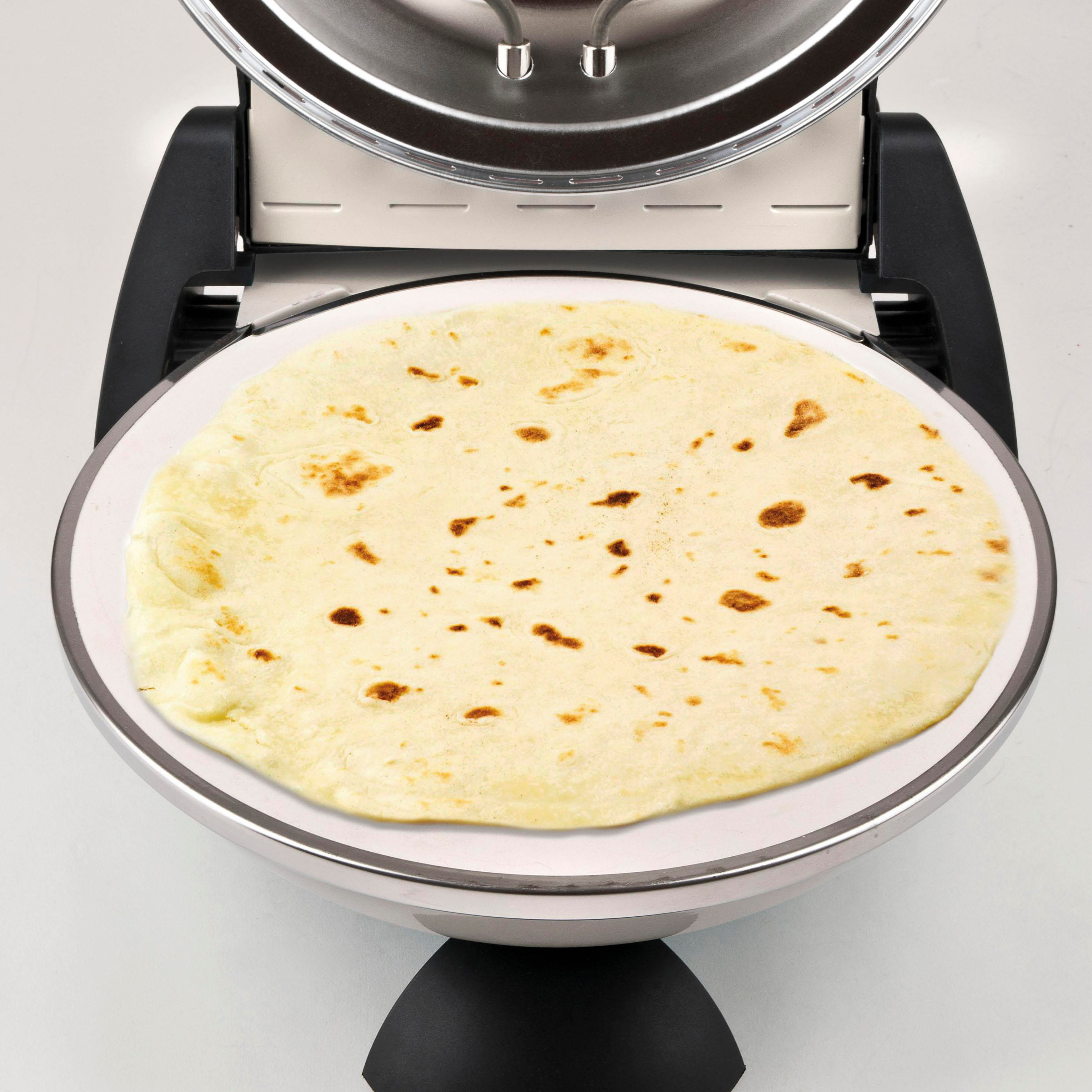 Eine Tortilla liegt in einer Grillplatte. Der Grill ist offen, und die Tortilla ist goldbraun mit dunklen Flecken.