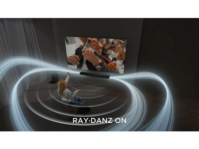 Egy nő ül és felemeli a kezét. Egy TV hegedűművészt mutat. Hanghullámok sugároznak egy soundbar-ból. Szöveg: RAY.DANZ ON.