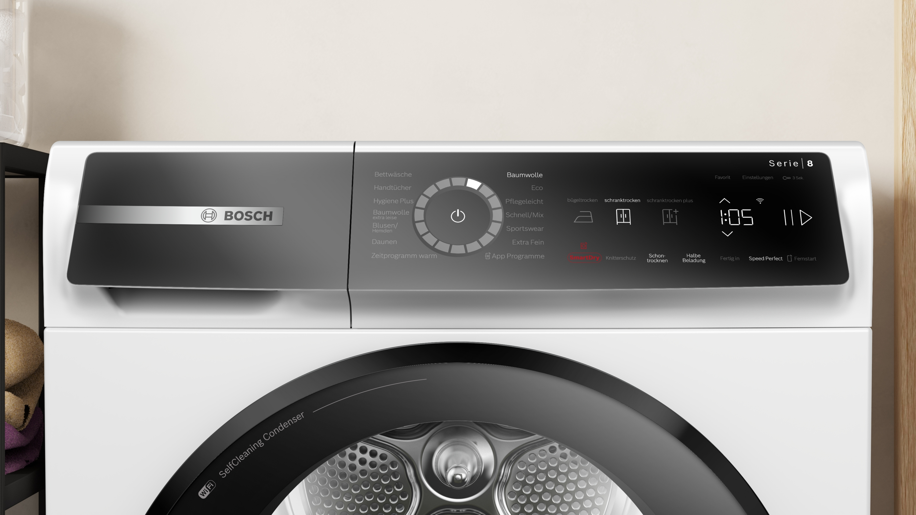 Ein weißer Bosch Serie 8 Trockner. Er hat ein schwarzes Bedienfeld mit Programmen und eine Digitalanzeige mit Uhrzeit.