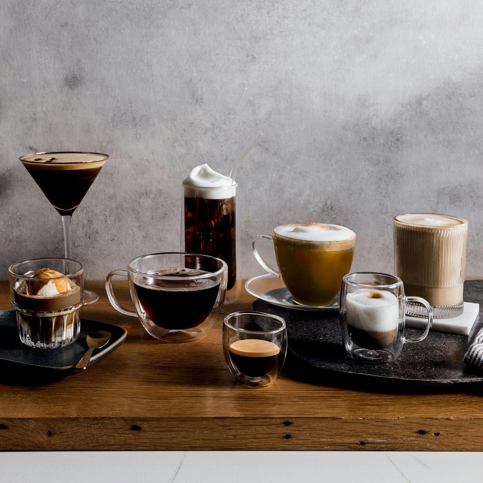 Különféle kávéitalok egy faasztalon. Ide tartozik az eszpresszó, affogato, jegeskávé, latte és cappuccino.
