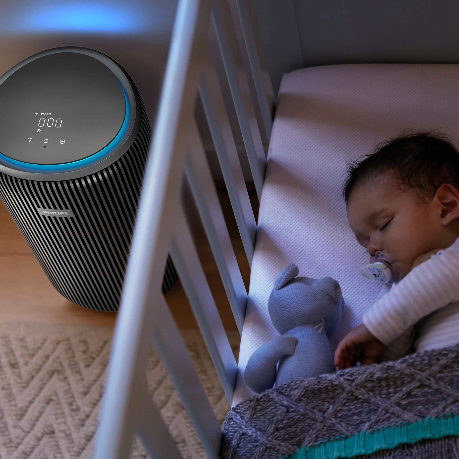 Un bébé dort dans un berceau avec une tétine. Un purificateur d'air en arrière-plan.