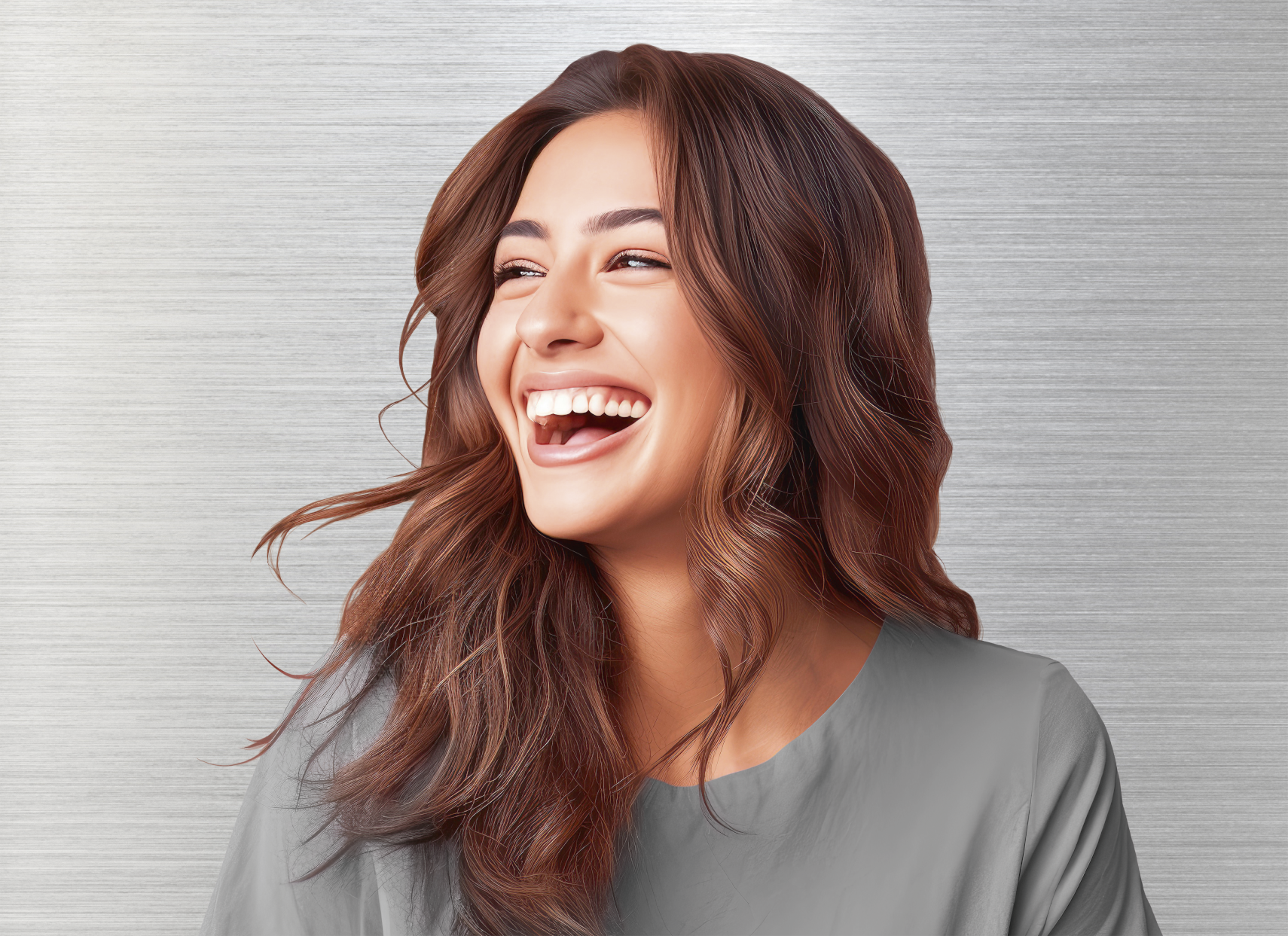 Femme aux cheveux bruns ondulés rit, montrant des dents blanches. Elle porte un haut gris sur fond argenté.