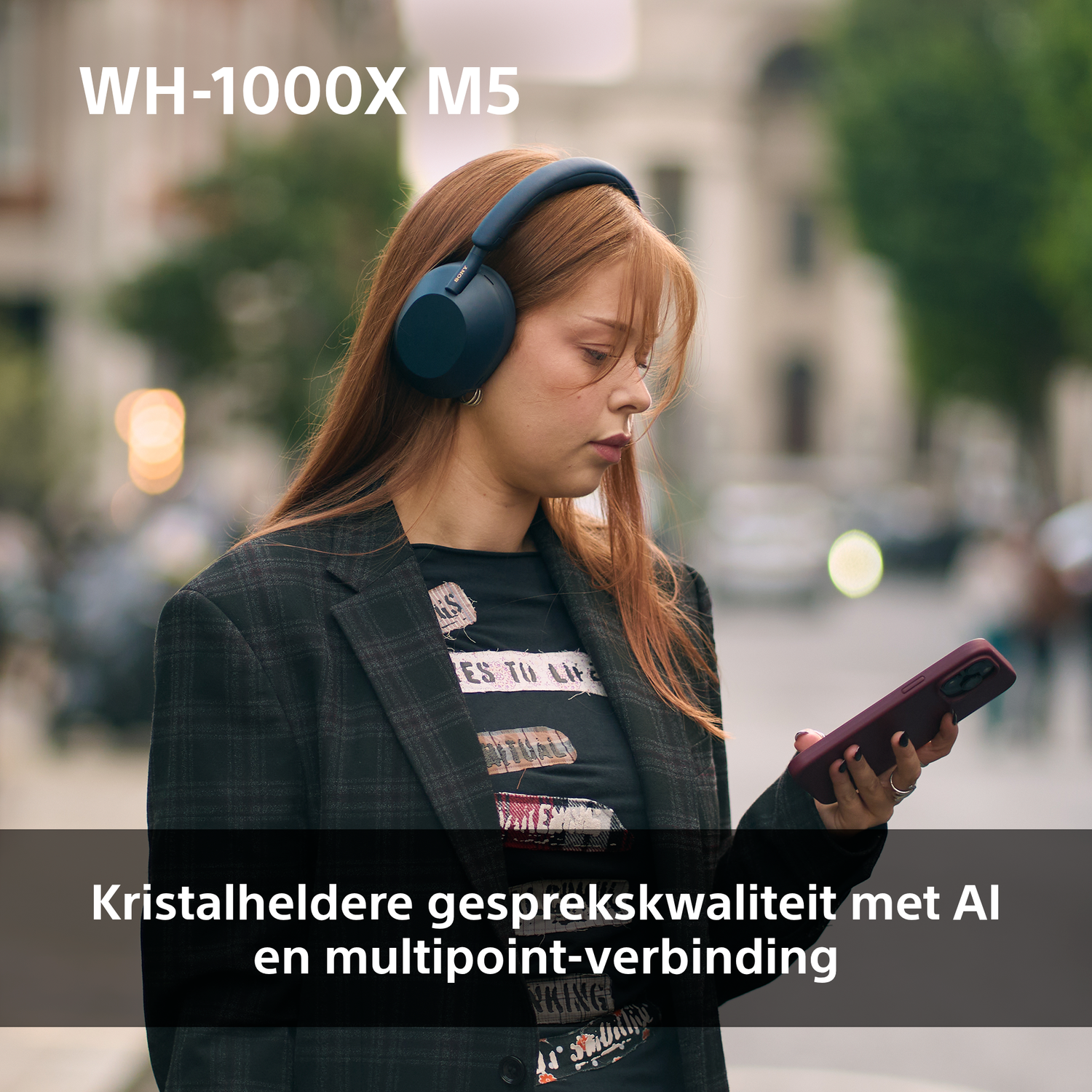Een vrouw met een koptelefoon en blazer houdt een telefoon vast. Tekst op het shirt en hieronder: 'Kristalheldere gesprekskwaliteit met AI'.