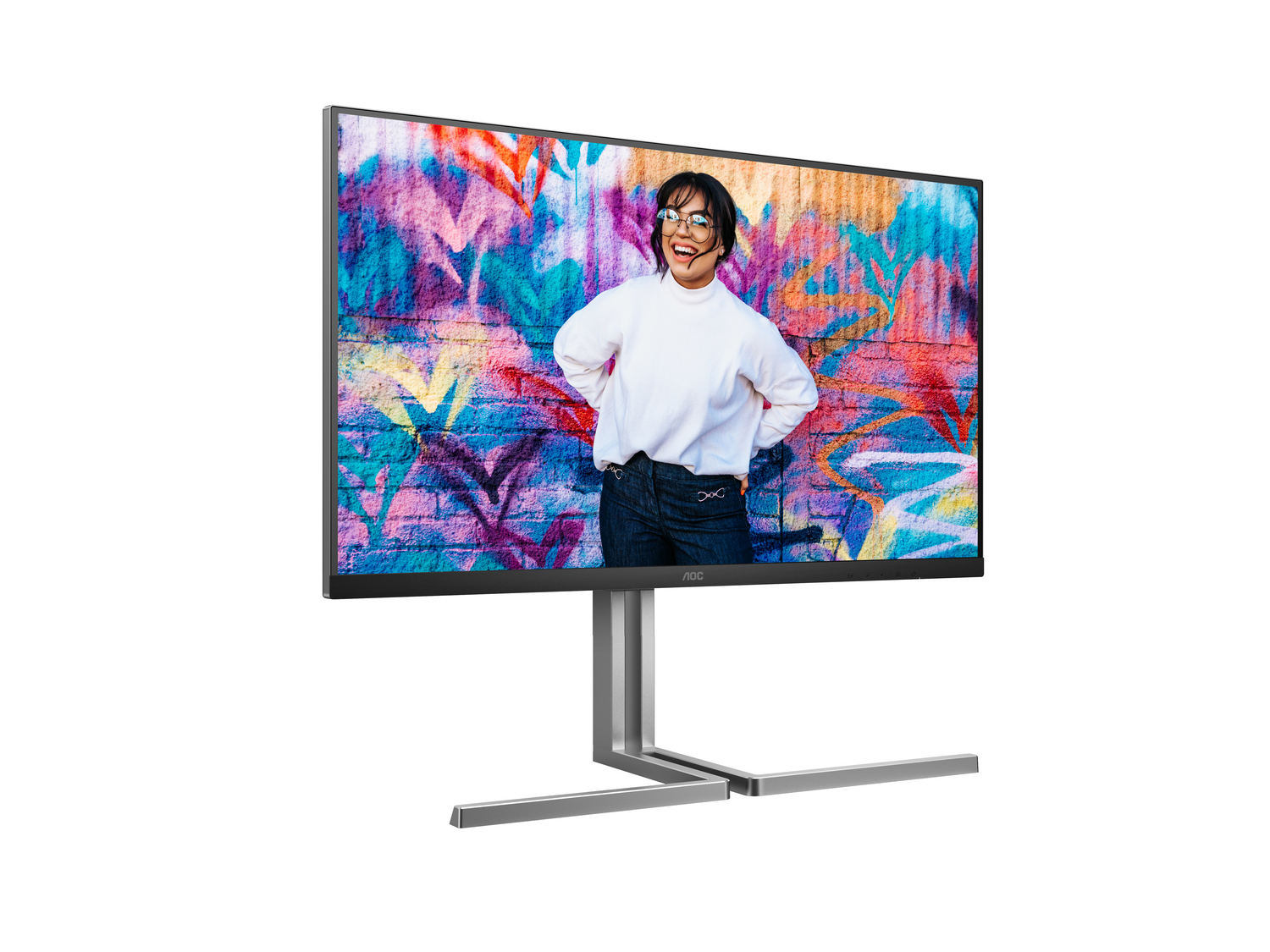 El monitor AOC muestra a una mujer sonriendo frente a una pared de graffiti. Lleva camisa blanca, vaqueros y gafas. El monitor es plateado.