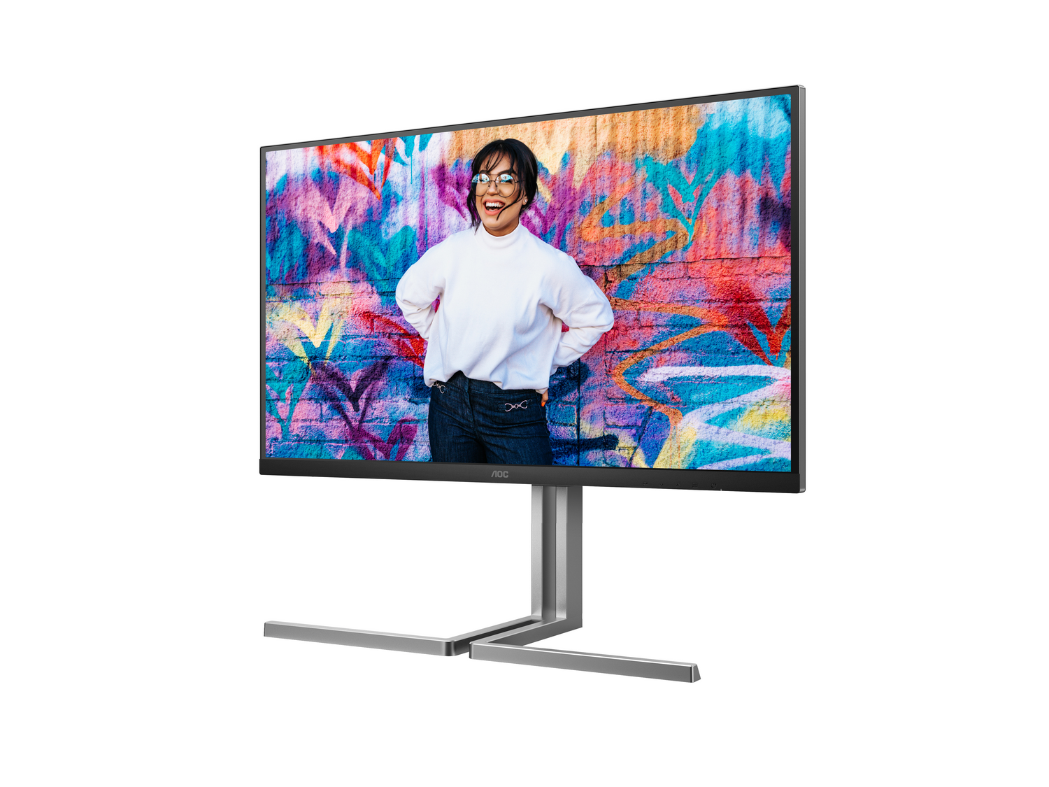 Un monitor muestra a una mujer frente a una colorida pared de graffiti. El monitor tiene un soporte plateado. La mujer sonríe.