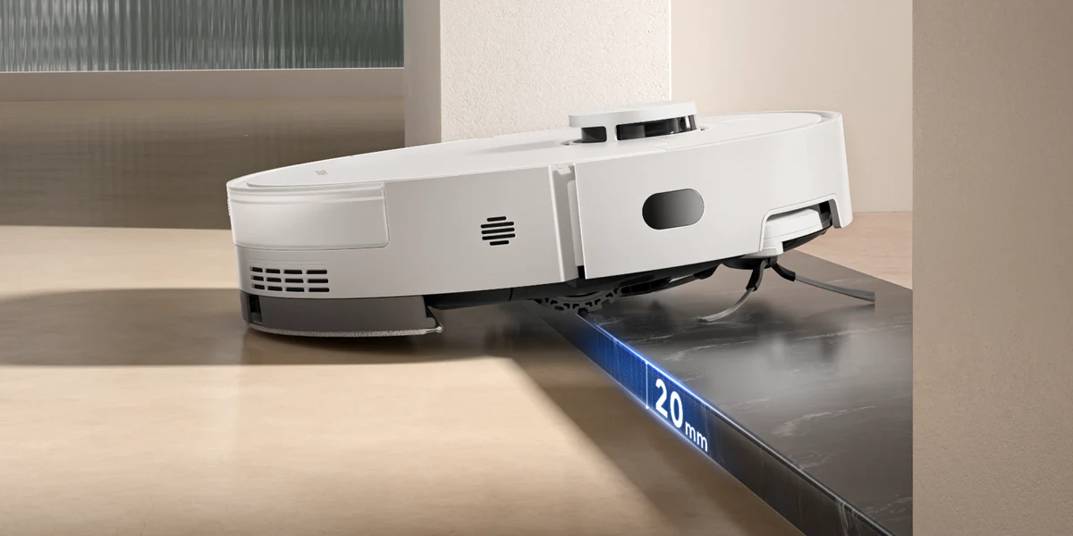 Egy fehér robotporszívó fekete felületen. A szélén 20 mm-es magasságjelző található. A háttér világos.