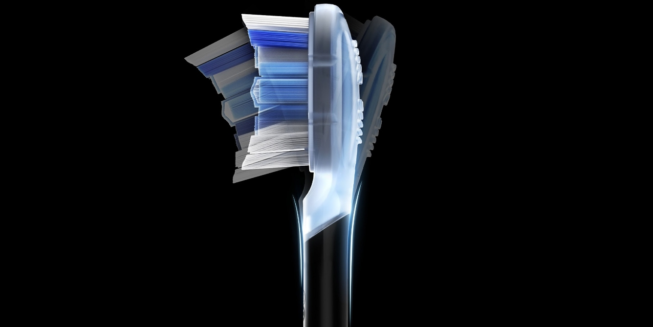 Zbliżenie główki szczoteczki do zębów. Włosie jest białe i niebieskie. Rękojeść jest czarna. Tło jest czarne.