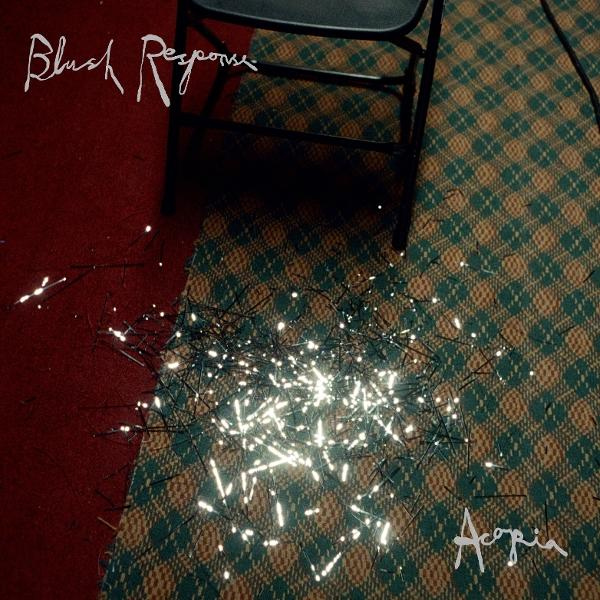 Ein Stuhl wirft einen Schatten auf einen gemusterten Teppich. Lichterketten beleuchten den Vordergrund. Text sagt 'Blush Response' und 'Acopia'.