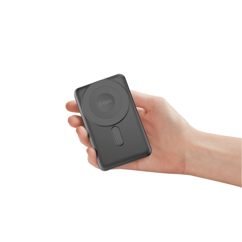 Bir el, koyu gri, dikdörtgen bir powerbank tutuyor. Dairesel bir manyetik şarj pedi ve oval bir kesimi var.