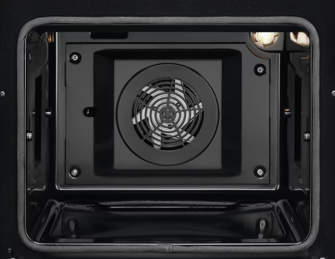 Wnętrze piekarnika. Wentylator pośrodku, otoczony czarnym panelem. Światło u góry. Piekarnik jest czarny.