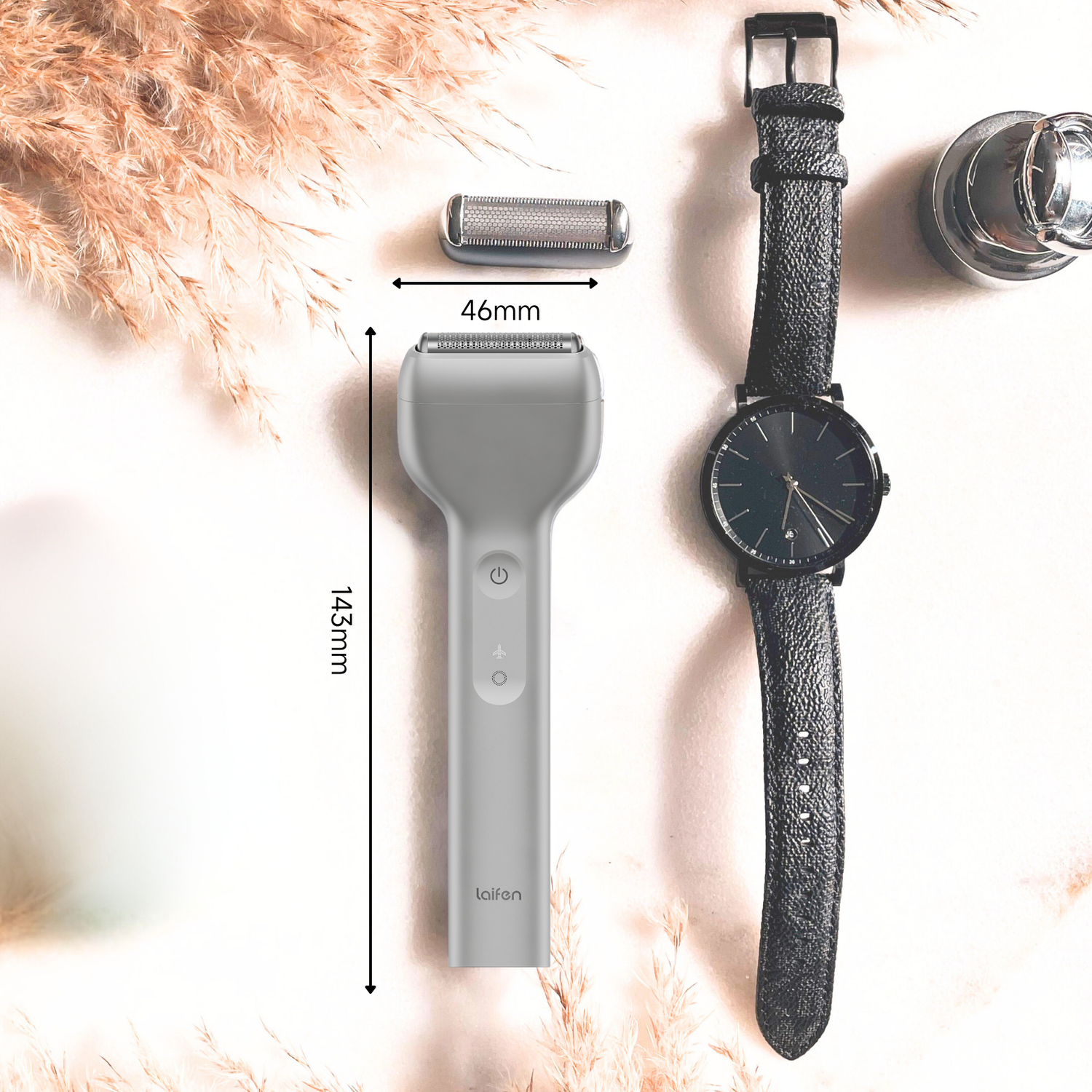 A flat lay featuring a gray shaver, a watch with black strap, and a shaver head. Dimensions are marked in mm.