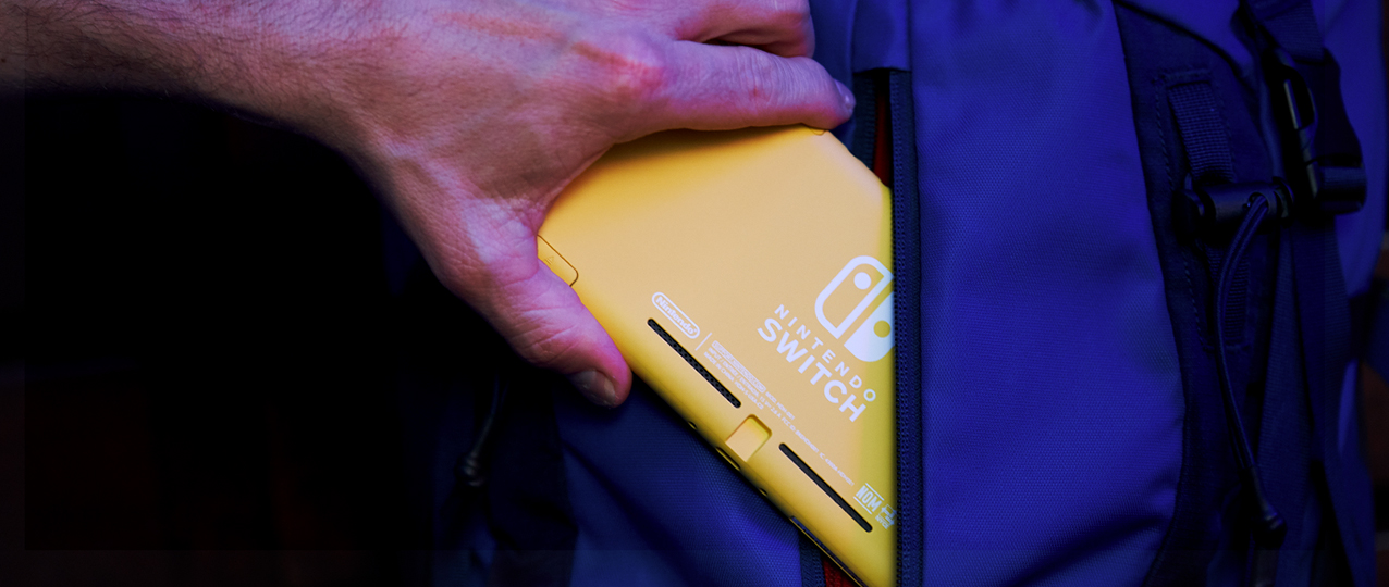 Una mano inserisce un Nintendo Switch giallo in una tasca blu di uno zaino. Il logo Switch è visibile.