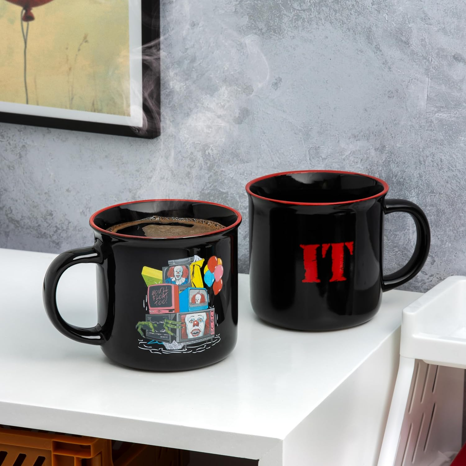 Két fekete bögre fehér felületen. Az egyiken IT design, a másikon TV képek. Gőz emelkedik. A háttér szürke.