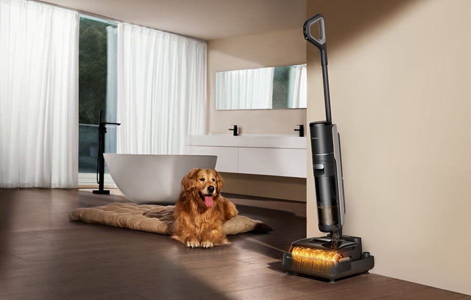 Egy golden retriever egy szőnyegen fekszik a fürdőszobában. Egy porszívó a falnak támaszkodik. Kád és mosdókagyló látható.