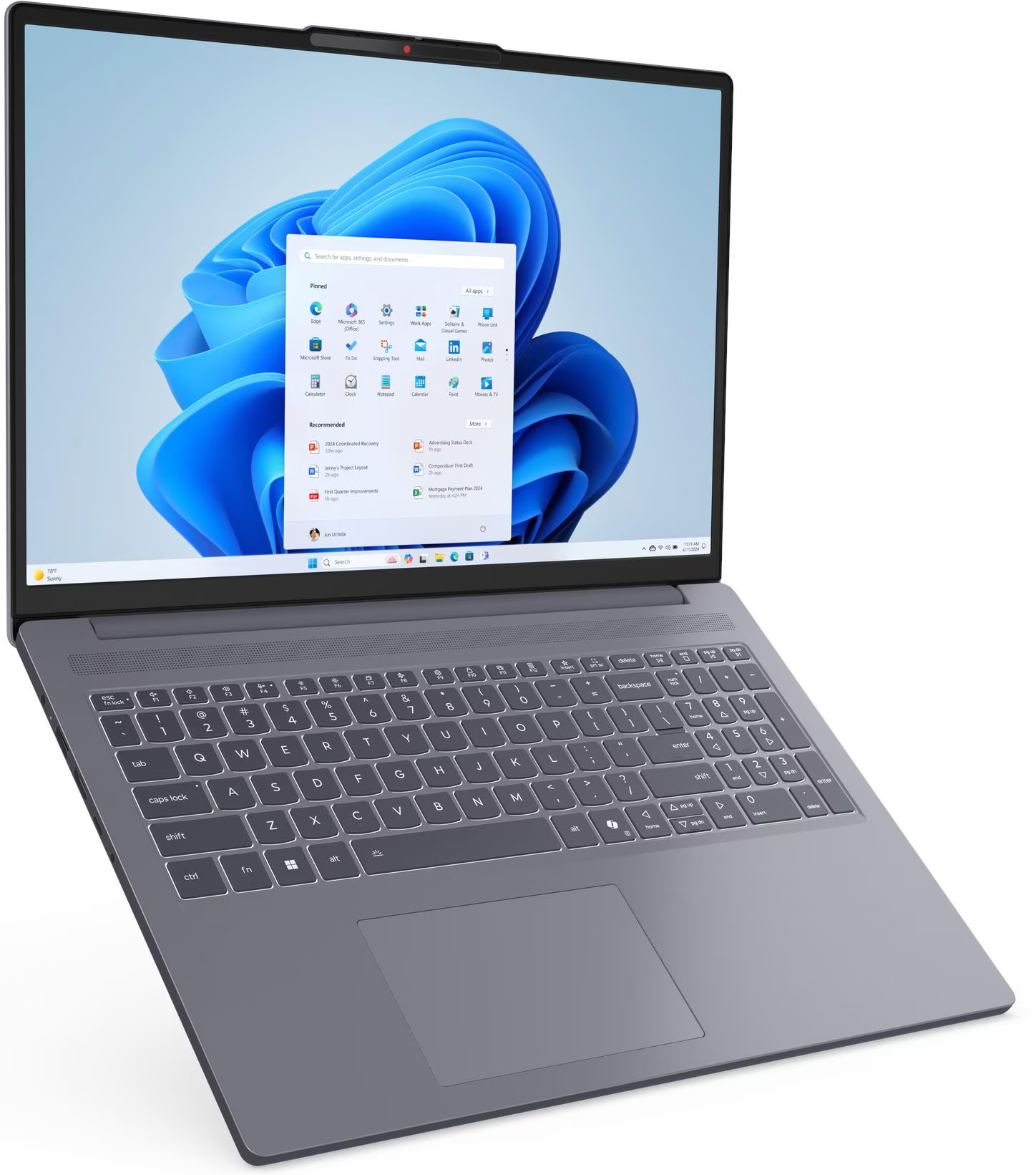 Egy laptop Windows 11 felületet jelenít meg. Van egy billentyűzete és egy érintőpadja. A képernyő alkalmazásikonokat és egy keresősávot mutat.