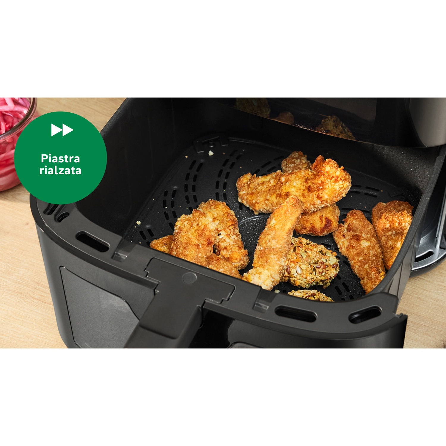 Una friggitrice ad aria con pezzi di pollo impanati cotti. Un pulsante verde con il testo italiano 'Piastra rialzata' a sinistra.