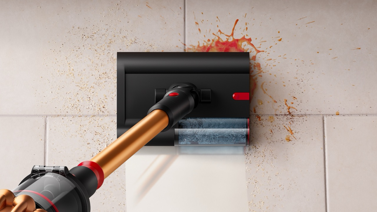Una herramienta de limpieza elimina manchas de una pared de azulejos. La herramienta es negra y dorada, con detalles en rojo. Las manchas son naranjas y marrones.