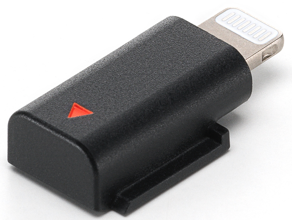 Adaptateur noir avec connecteur argenté. Un triangle rouge est sur la partie noire. L'adaptateur est posé sur une surface blanche.