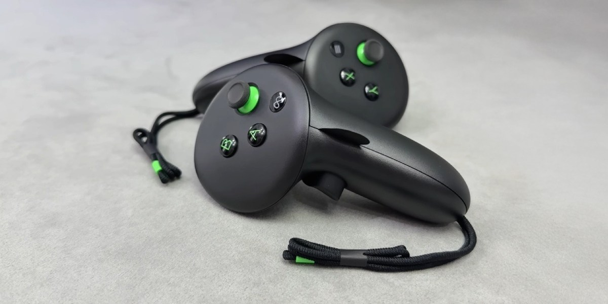 Dwa czarne kontrolery VR z zielonymi akcentami na szarej powierzchni. Każdy ma przyciski i pasek na dłoń. Tło jest gładkie.