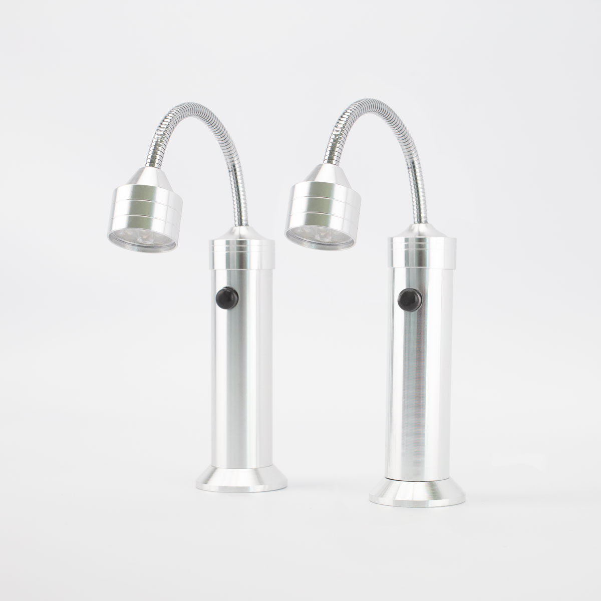 Zwei silberne LED-Leuchten mit flexiblen Hälsen stehen auf einer weißen Oberfläche. Jede hat einen Knopf an der Basis.