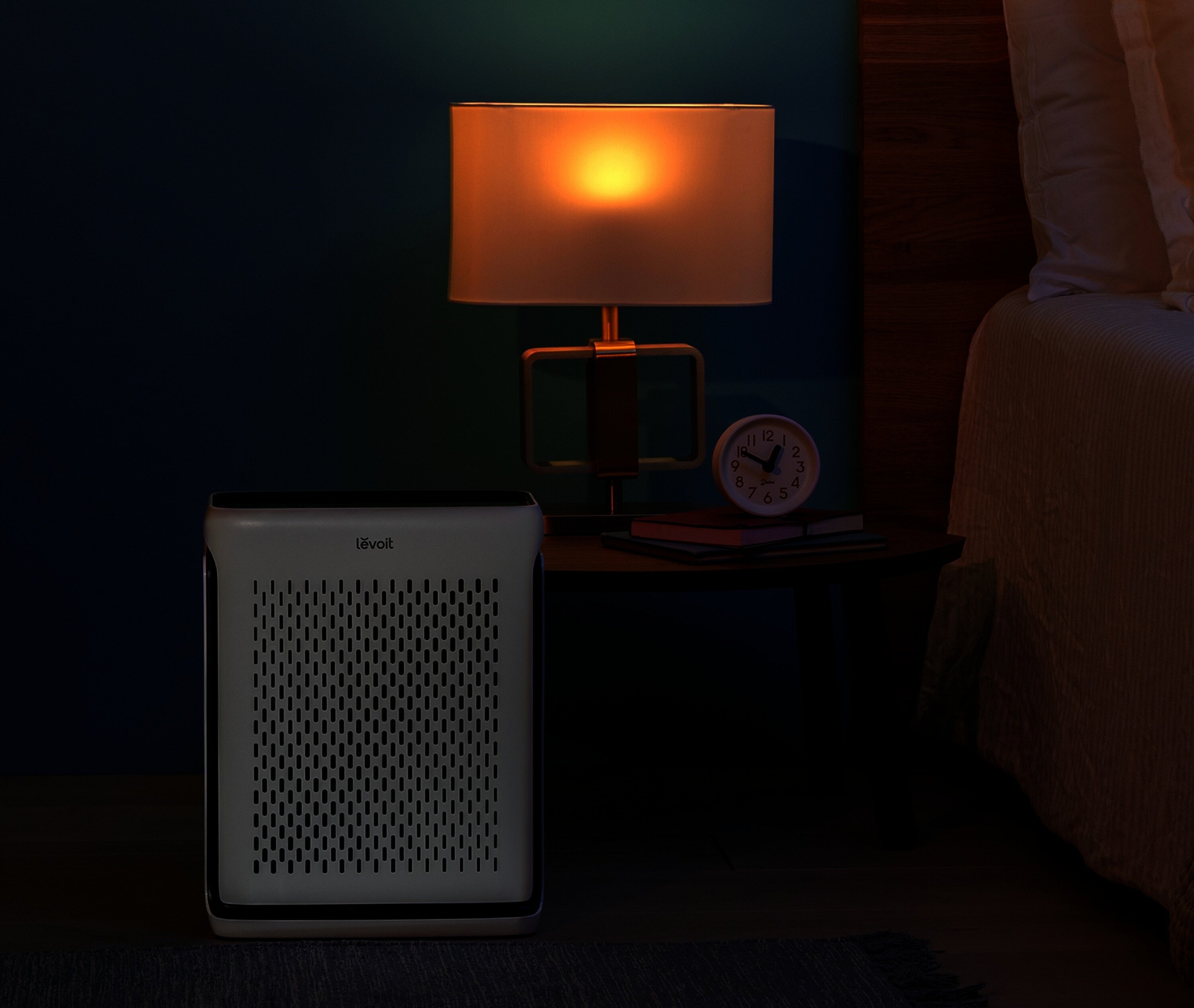 Scena sypialni z oczyszczaczem powietrza. Widoczna lampa, stolik nocny i łóżko. Pokój ma mroczny, przytulny nastrój.