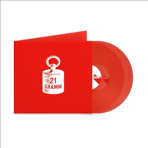 Rote Schallplatte und Hülle. Die Hülle zeigt eine weiße Grafik und den Text '21 GRAMM'. Die Platte ist rechts sichtbar.