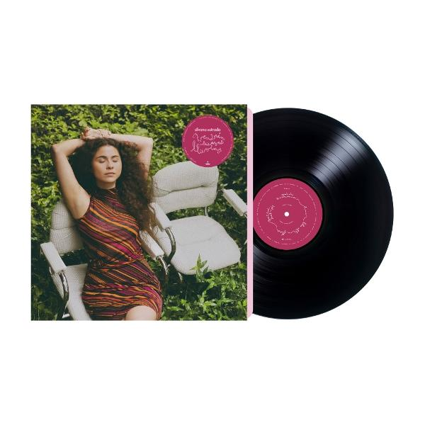 Albumcover mit Frau im gestreiften Kleid, sitzend, mit geschlossenen Augen. Vinyl-Schallplatte daneben, schwarz mit pinkfarbenem Etikett. Grüner Hintergrund.