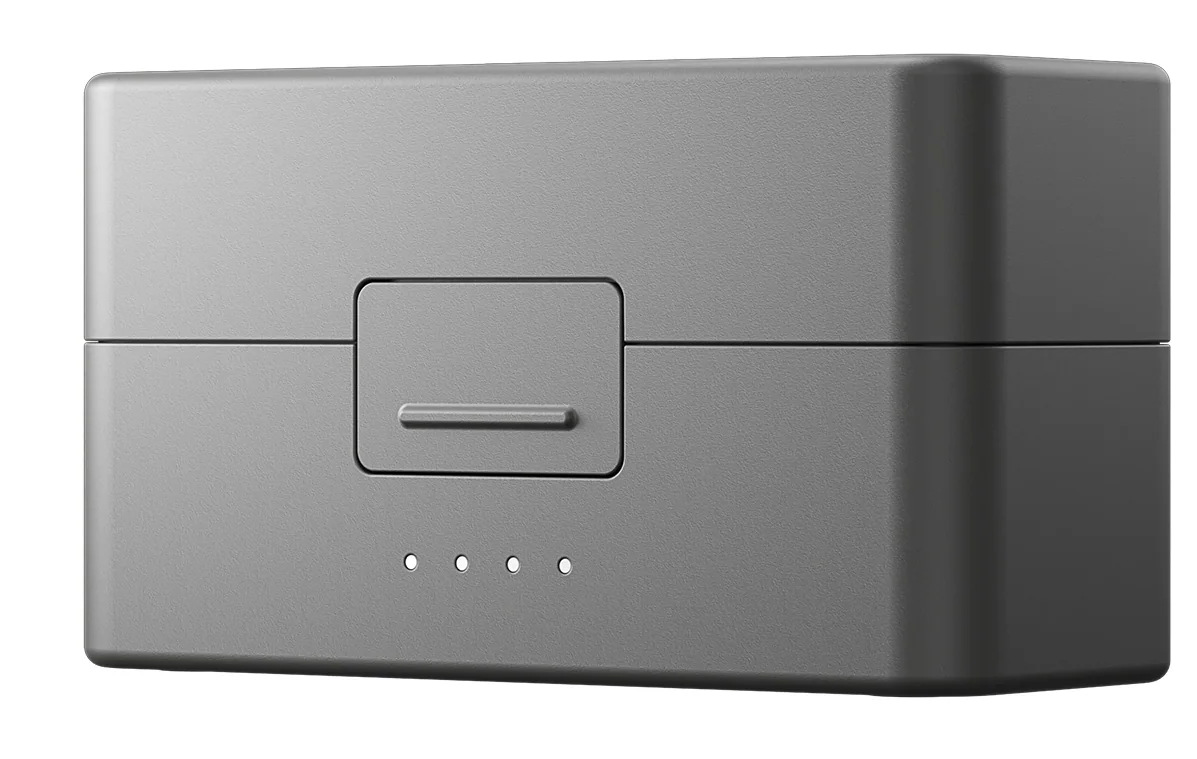 Pokazano szare etui ładujące. Ma prostokątny kształt z pokrywą i małym prostokątnym przyciskiem. Trzy małe kropki są wyrównane na dole.