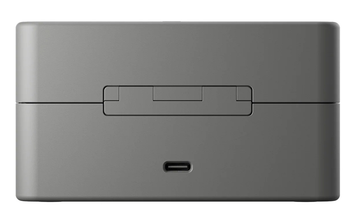 Zamknięte, szare etui ładujące do słuchawek. Ma prostokątny kształt z otwieraną pokrywą i portem USB-C u dołu.