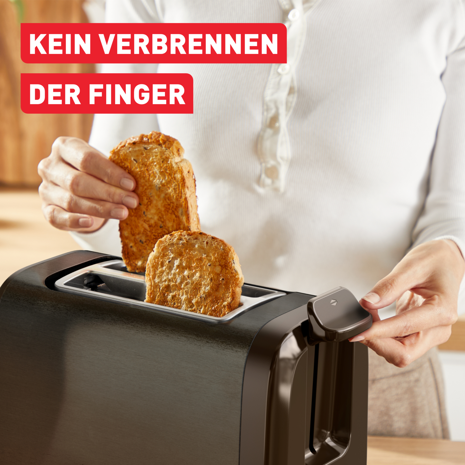 Person entnimmt Toast aus einem Toaster. Roter Text sagt 'KEIN VERBRENNEN DER FINGER'. Toaster ist schwarz und hat zwei Schlitze.