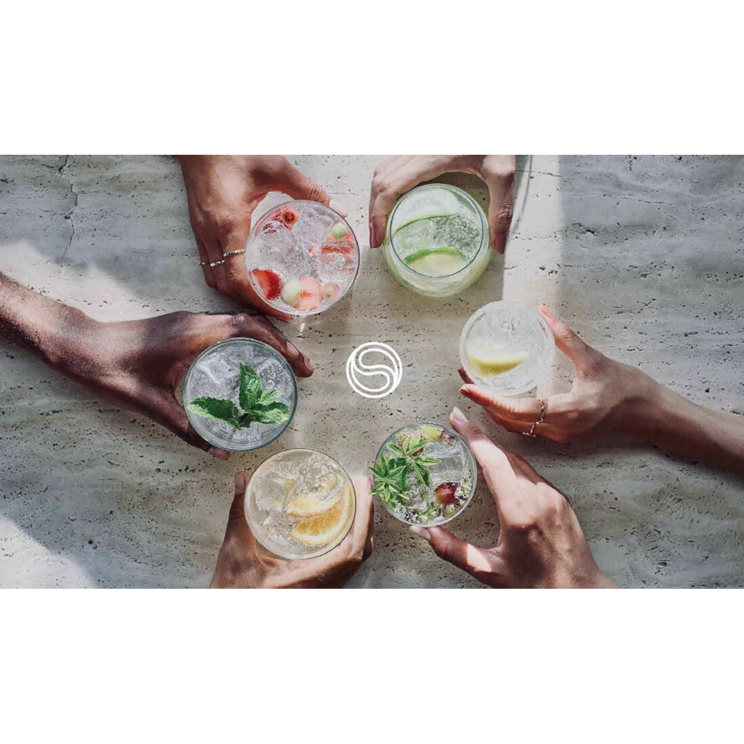 Hands holding six different cocktails with fruit and herbs, arranged in a circle on a stone surface. A logo is in the center.
