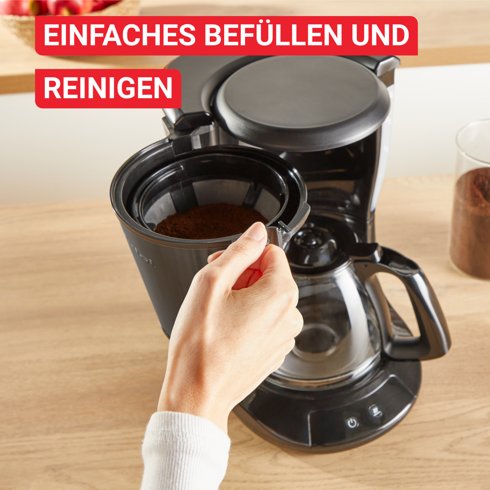 Eine Hand öffnet einen Kaffeefilter. Der Filter enthält Kaffeepulver. Oben steht: 'Einfaches Befüllen und Reinigen'.