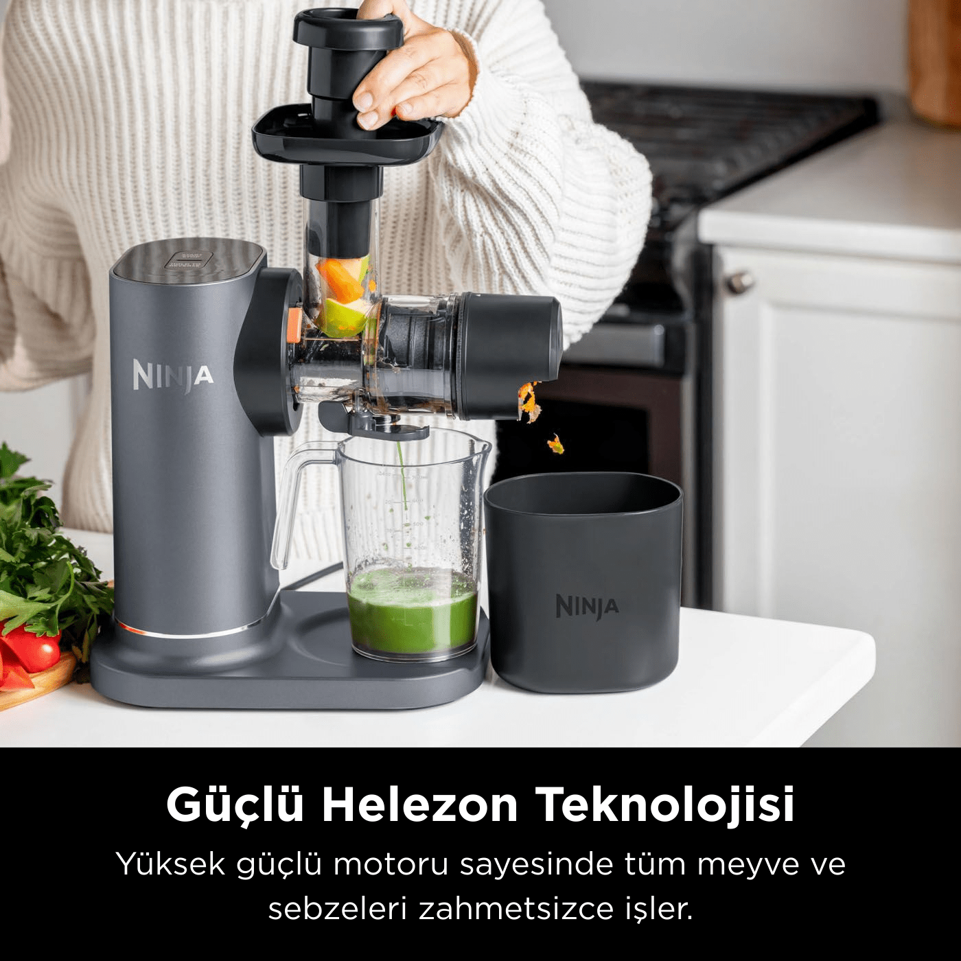 Bir kişi, Ninja sıkacağı kullanarak meyve suyu sıkıyor. Yeşil meyve suyu, meyve ve sebzeler içeren bir cam kap var.
