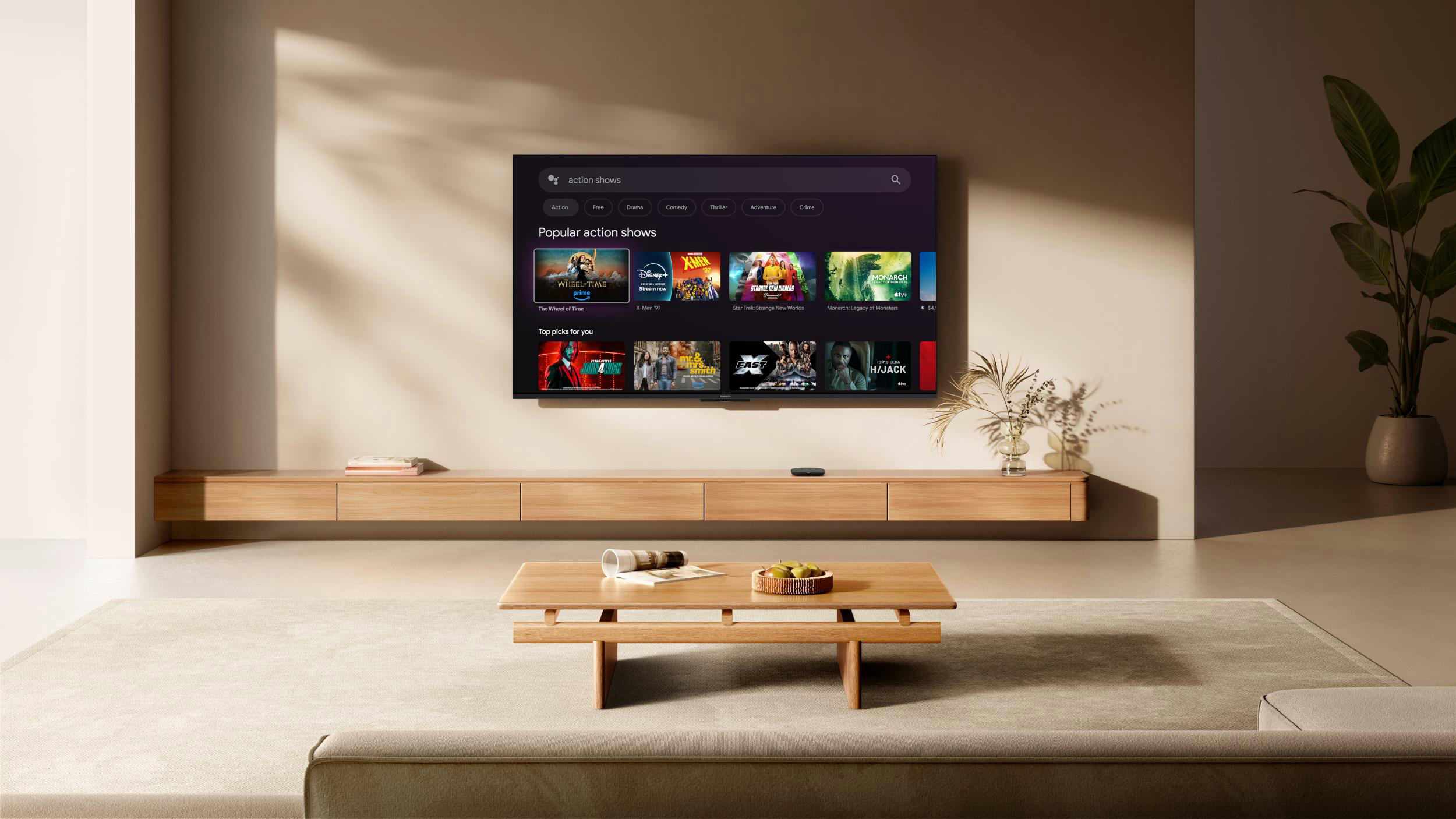Ein Wohnzimmer mit einem Fernseher, der Action-Shows zeigt. Ein Holztisch und ein Sofa stehen davor. Rechts ist eine Pflanze.
