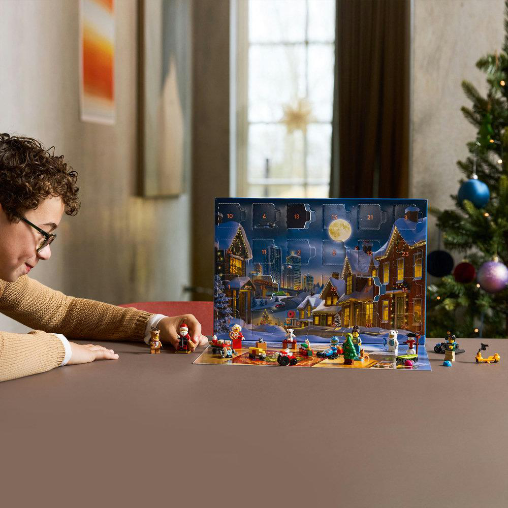 Eine Person betrachtet einen Weihnachtskalender mit kleinen Spielfiguren. Im Hintergrund ist ein Weihnachtsbaum zu sehen.
