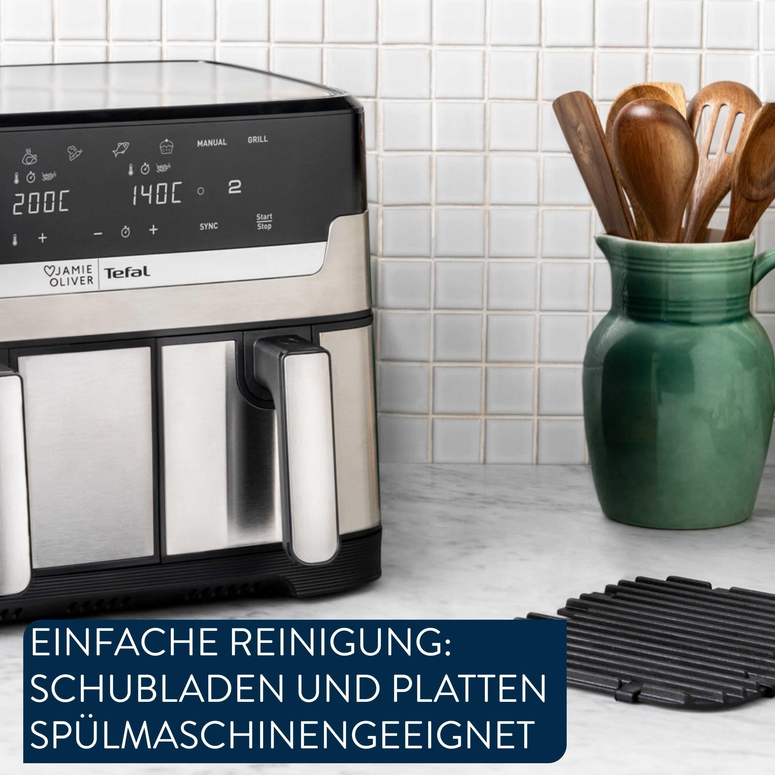 Ein Luftfritteuse mit Bedienelementen, Holzutensilien in einem grünen Krug und eine schwarze Grillplatte.