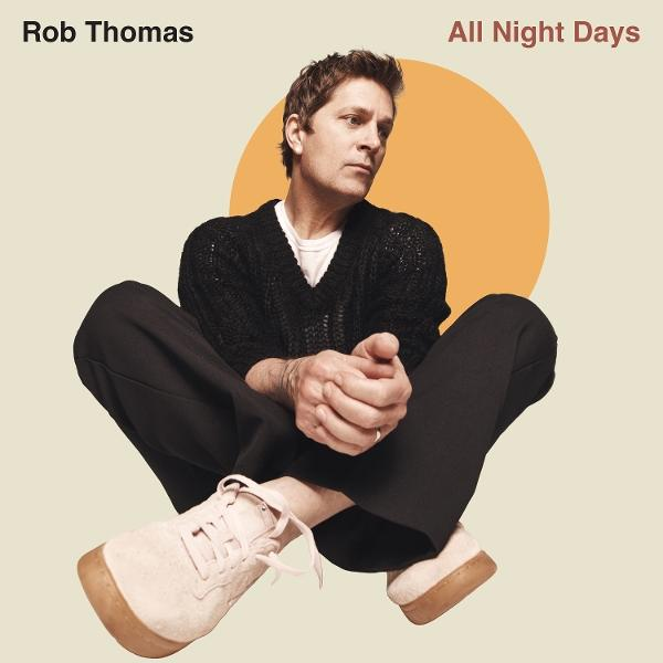 Rob Thomas sitzt und schaut weg. Er trägt einen schwarzen Pullover, eine Hose und helle Schuhe. Hinter ihm ist ein orangefarbener Kreis, der Titel lautet All Night Days.