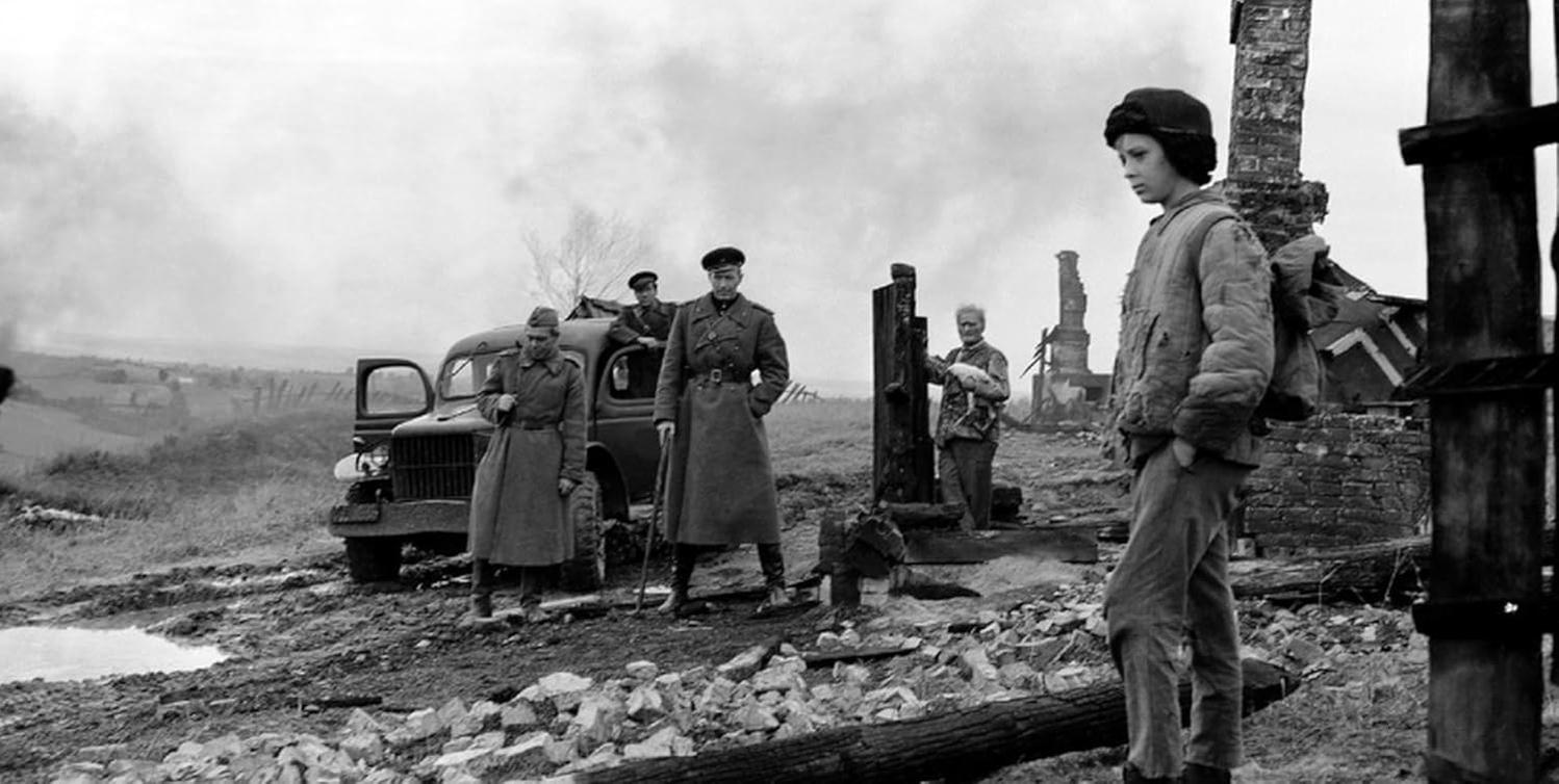 Schwarz-Weiß-Bild. Soldaten stehen in der Nähe eines Lastwagens inmitten von Trümmern und Rauch. Ein Junge schaut zu.